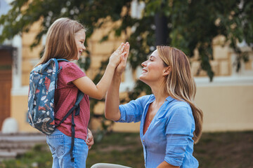 Happy family preparing for school. Little girl with mother. Mother saying goodbye to her daughter...