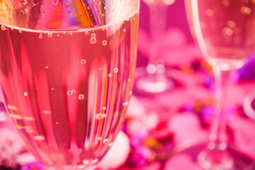 Wine glasses with sparkling wine on a lilac background and golden confetti.	