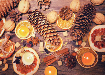Festive composition of natural cones, nuts, dried orange slices, spices and tea candles on the theme of Thanksgiving and Christmas
