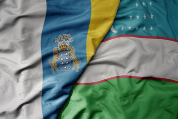 big waving national colorful flag of uzbekistan and national flag of canary islands .