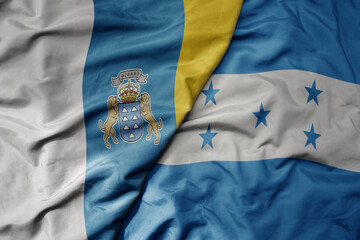 big waving national colorful flag of honduras and national flag of canary islands .