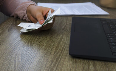 A man holds receipts from shops in front of a laptop.