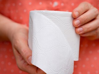 A close-up shot of a toilet paper roll in woman hands.
