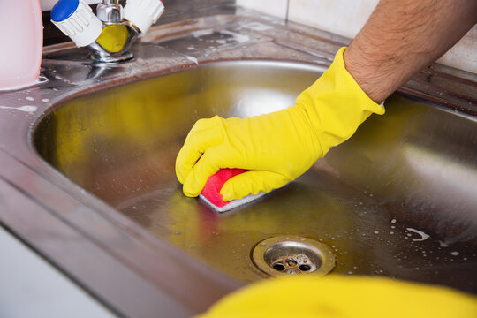 Cleaning Kitchen Sink with Sponge and Gloves