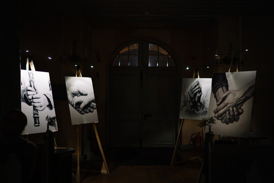 Valmiera, Latvia - January 7, 2024 - Saint Simon's Church. Pencil drawings of hands on easels highlighted in a dimly lit room with an arched doorway in the background.