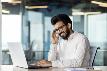 Young indian man businessman and office worker suffering from severe headache and tension. He sits...
