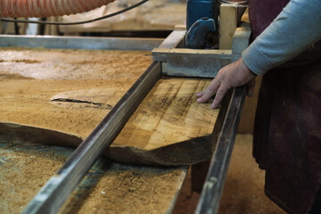 Focused and steady, an artisan slices through wood with a bandsaw. This tool is essential for his meticulous craft.