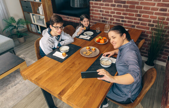 From above of mother captures a photo of her children enjoying breakfast at home, featuring a warm and inviting dining setting