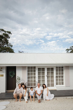 Family of three generations sitting together on front deck of home