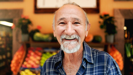 Latin senior man shopping at farm market. Customer buying at grocery store. Small business concept