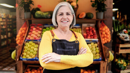 Small business senior woman outside farmer market looking at camera. Latin American owner working at supermarket vegetable store
