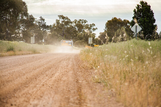 Truck driving down dirt road with dust cloud behind