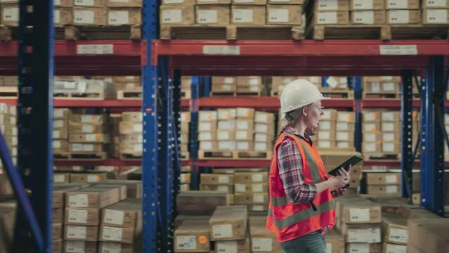Two warehouse employees, outfitted with hard hats and high-visibility vests, walking going organize and verify goods on the storage racks. Warehouse Inventory Management in Action
