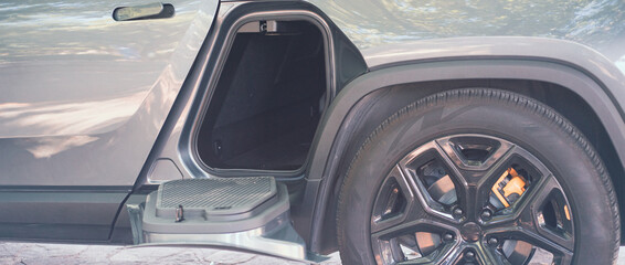 Panorama horizontal storage space gear tunnel be accessed from either side of modern electric vehicle pickup truck outdoor, special accessories compartment underneath second row passenger seats