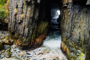 australia sea cave with waves crashing through it in tasmania