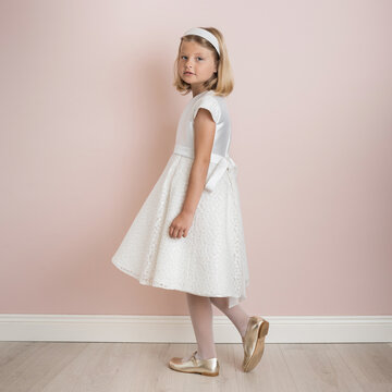 blonde girl 9 years old in a white festive dress on a pale pink background, dress for a wedding, first communion, birthday, celebration