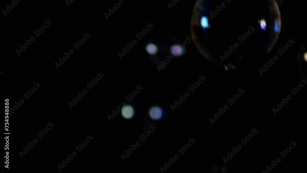 Poster flying and falling transparent soap bubbles in dark on a black background. a lot of colored soap bub