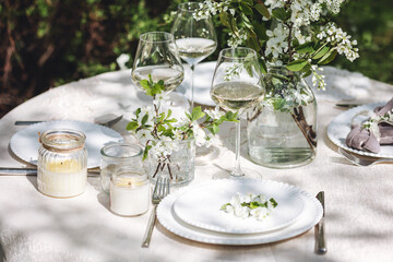 Rustic zero waste wedding decor with natural elements. Fresh spring blooming flowers, candles, linen napkins, wine glasses. Eco friendly decoration for the special holiday dinner. Romantic cozy place