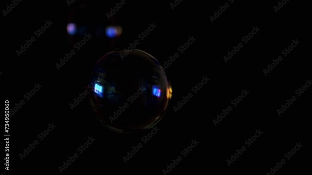 Poster flying and falling transparent soap bubbles in dark on a black background. a lot of colored soap bub