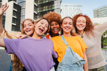 Social group of real young women are smiling and posing in front of a building, showing happy...