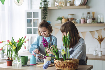 Happy mother and daughter doing home gardening together in the kitchen, taking care about flowers, plants. Family traditions and quality time, having fun, enjoy domestic life. Mother's or Women's day - obrazy, fototapety, plakaty