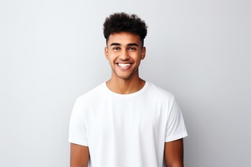 Obraz premium Happy young boy in white t-shirt presenting empty shirt for advertising in studio photo shoot