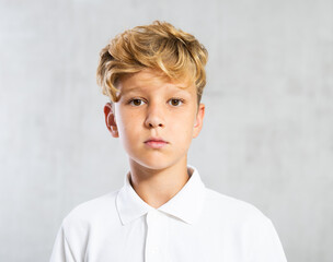 Positive boy in casual clothes posing while sitting on chair