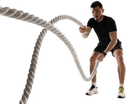 Concentrated athletic man training, doing workout exercises with rope isolated on transparent background. Concept of sport, fitness, workout, healthy and active lifestyle