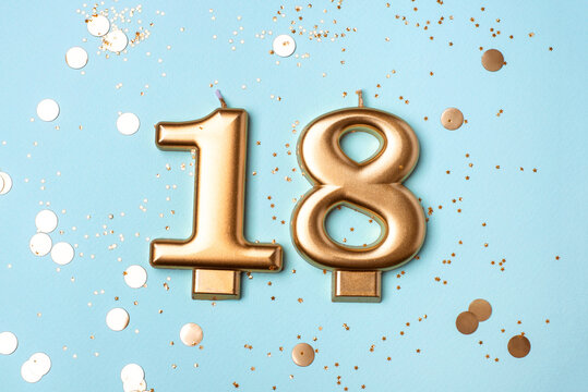 Gold candles in the form of number eighteen on blue background with confetti. 18 years celebration. Greeting banner.