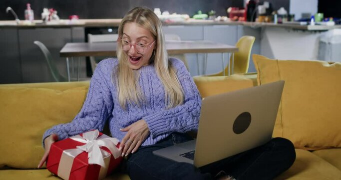 Young and appealing woman secures gift by playing online games using laptop. Lady receives present from online market as valued regular customer