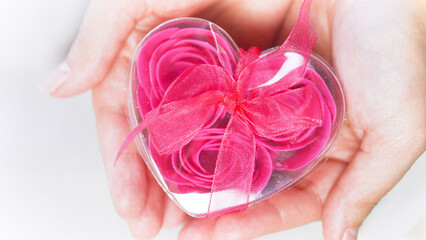 Valentine's Day concept. Pink roses in a heart-shaped box in female hands.