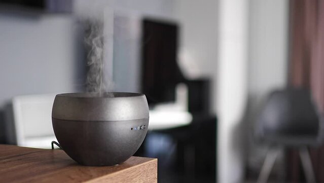 Grey aroma oil diffuser on light table at home, air freshener