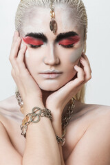 Close-up portrait of a beautiful girl painted with body painting in chains, bracelets and other jewelry