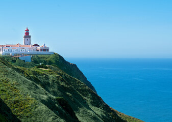 Fototapeta na wymiar White lighthouse on cliffs with sea view Cabo da Roca. Portugal