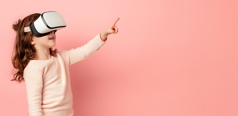 A little girl wearing VR glasses on a plain pink background on the left edge points his finger at an empty space. Copy space