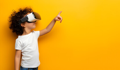 A little boy wearing VR glasses on a plain yellow background on the left edge points his finger at an empty space. Copy space