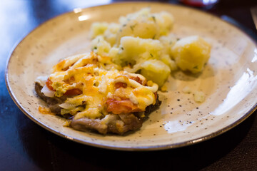 Meat baked with cheese with boiled potatoes served on a plate in restaurant