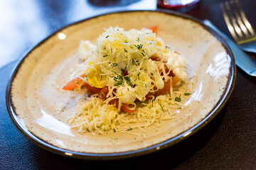 Mix of tomatoes, cheese, eggs with mayonnaise on a plate in a restaurant