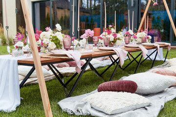 Pink girle aesthetic picnic table setting with pink flowers bouquets, cozy pillows, candles decor...