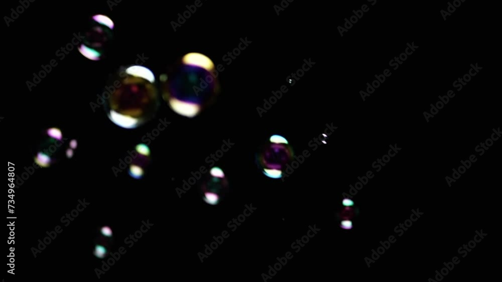 Poster colorful soap bubbles fly in empty space on isolated black background. colorful lights. many rainbow