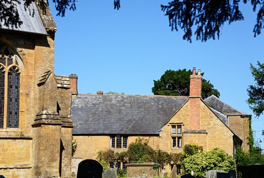 View of All Saints church and graveyard with traditional town buildings to the rear along Church Street, Martock, Somerset, UK, Europe