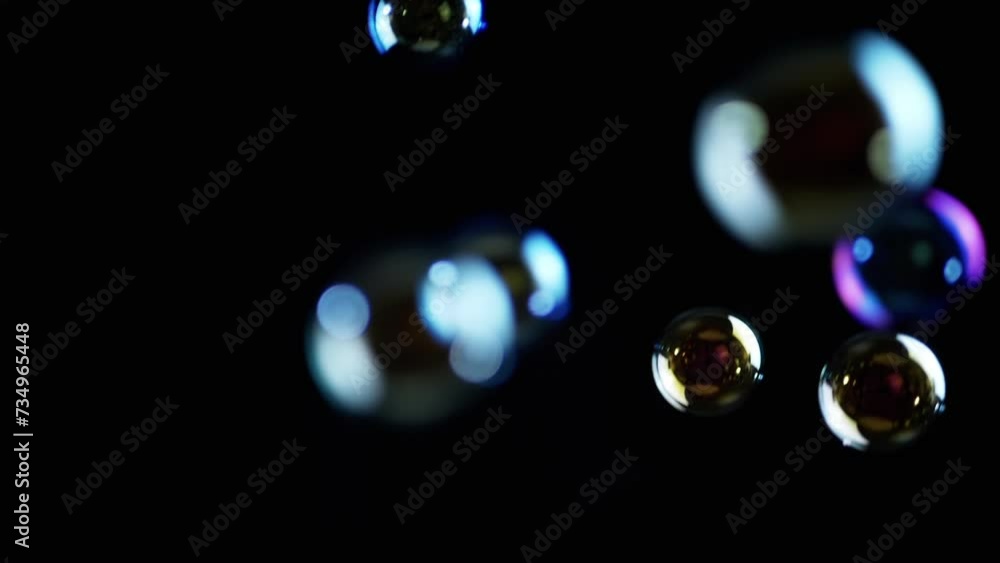 Poster colorful soap bubbles fly in empty space on isolated black background. colorful lights. many rainbow