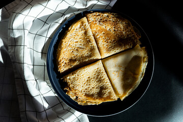 Fresh thin pancakes on a dark plate in the kitchen, dark background, shot on top, concept of...