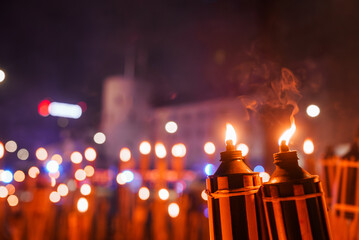 Handheld torches illuminate a Latvian Independence Day celebration at night, with a warm glow and...