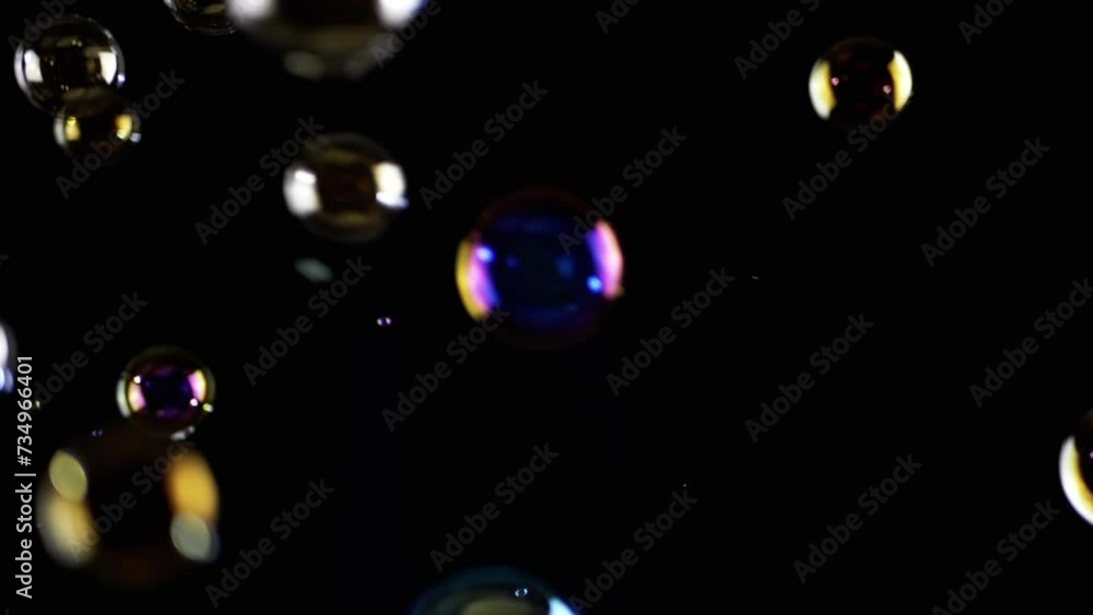 Poster colorful soap bubbles fly in empty space on isolated black background. colorful lights. many rainbow
