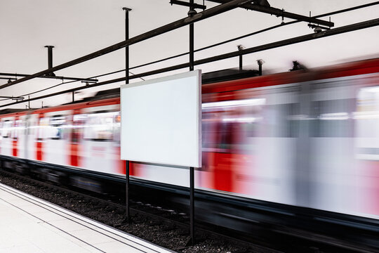 Fast-moving train passing by a blank billboard at station