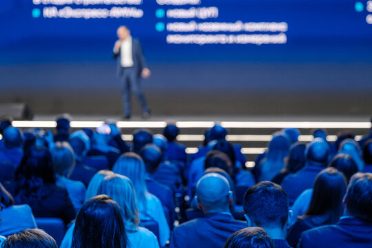 Corporate event with a speaker on stage and an audience of attentive professionals in a seminar or conference. - Powered by Adobe