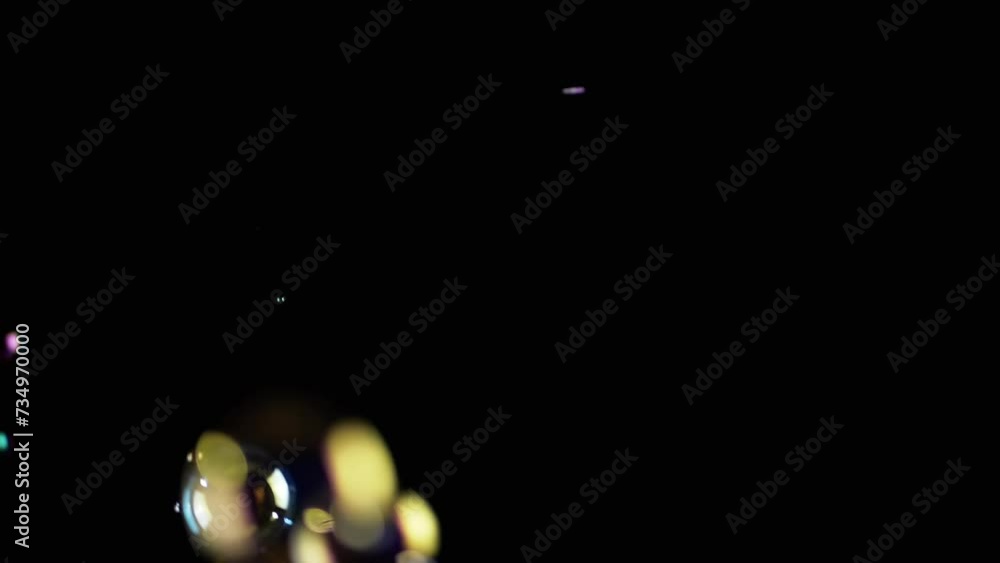Poster colorful soap bubbles fly in empty space on isolated black background. colorful lights. many rainbow