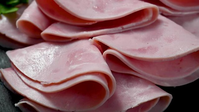 Processed meat. Delicious ham slices in a plate, over dark background