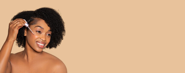 Black woman applying serum for glowing skin care